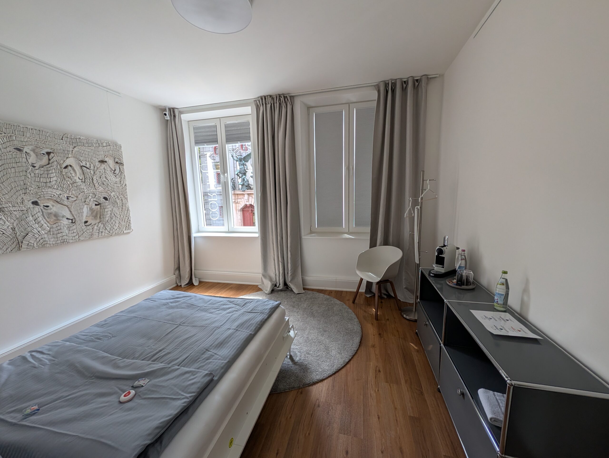 Schlafraum der Praxis mit Bett, Fenster und Sideboard